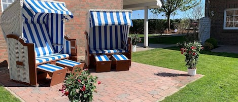 Une terrasse avec deux chaises longues à rayures et une plante en pot.
