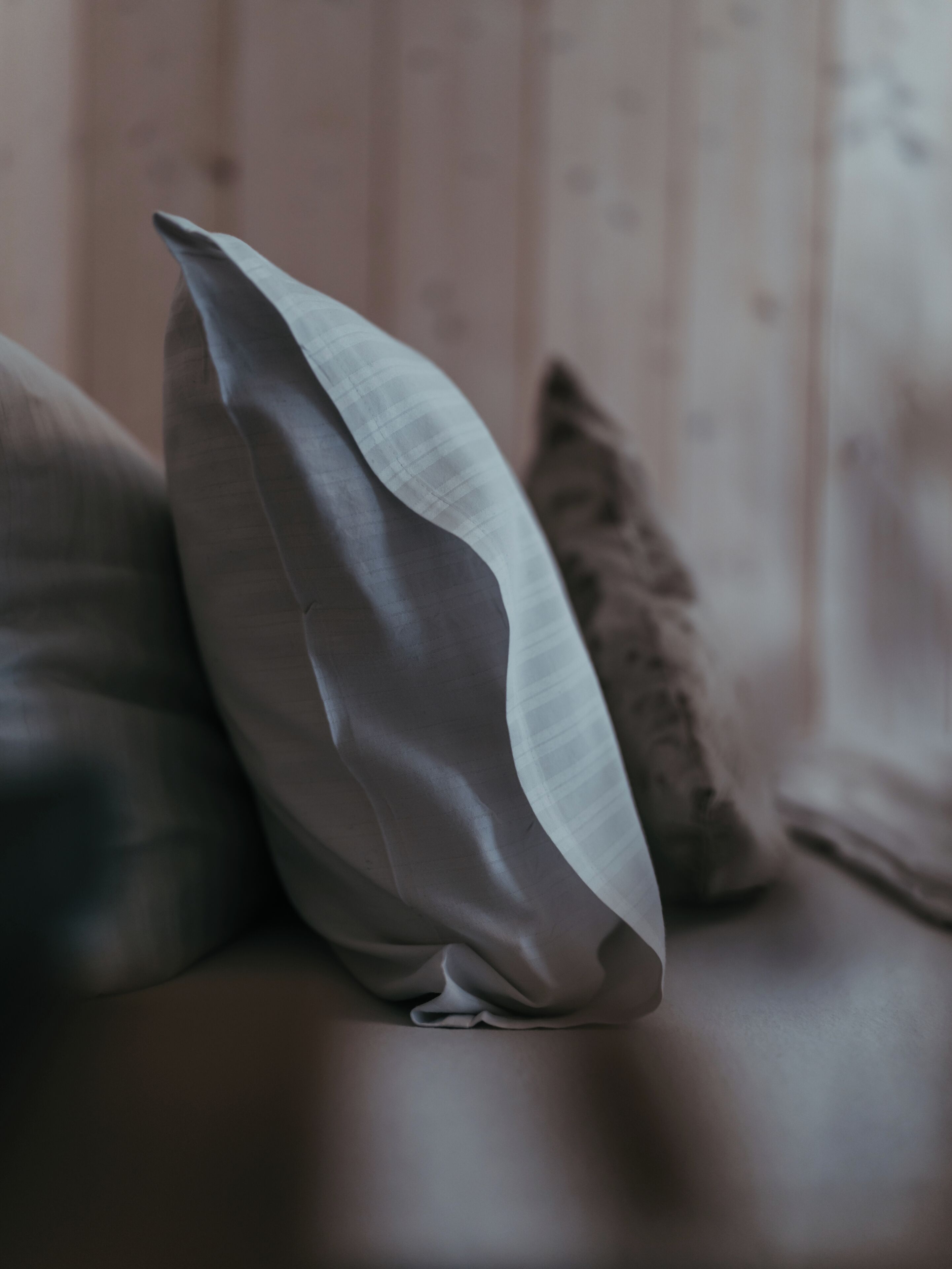 A close-up of a pillow with a textured fabric, placed on a surface with a soft, neutral-toned background.
