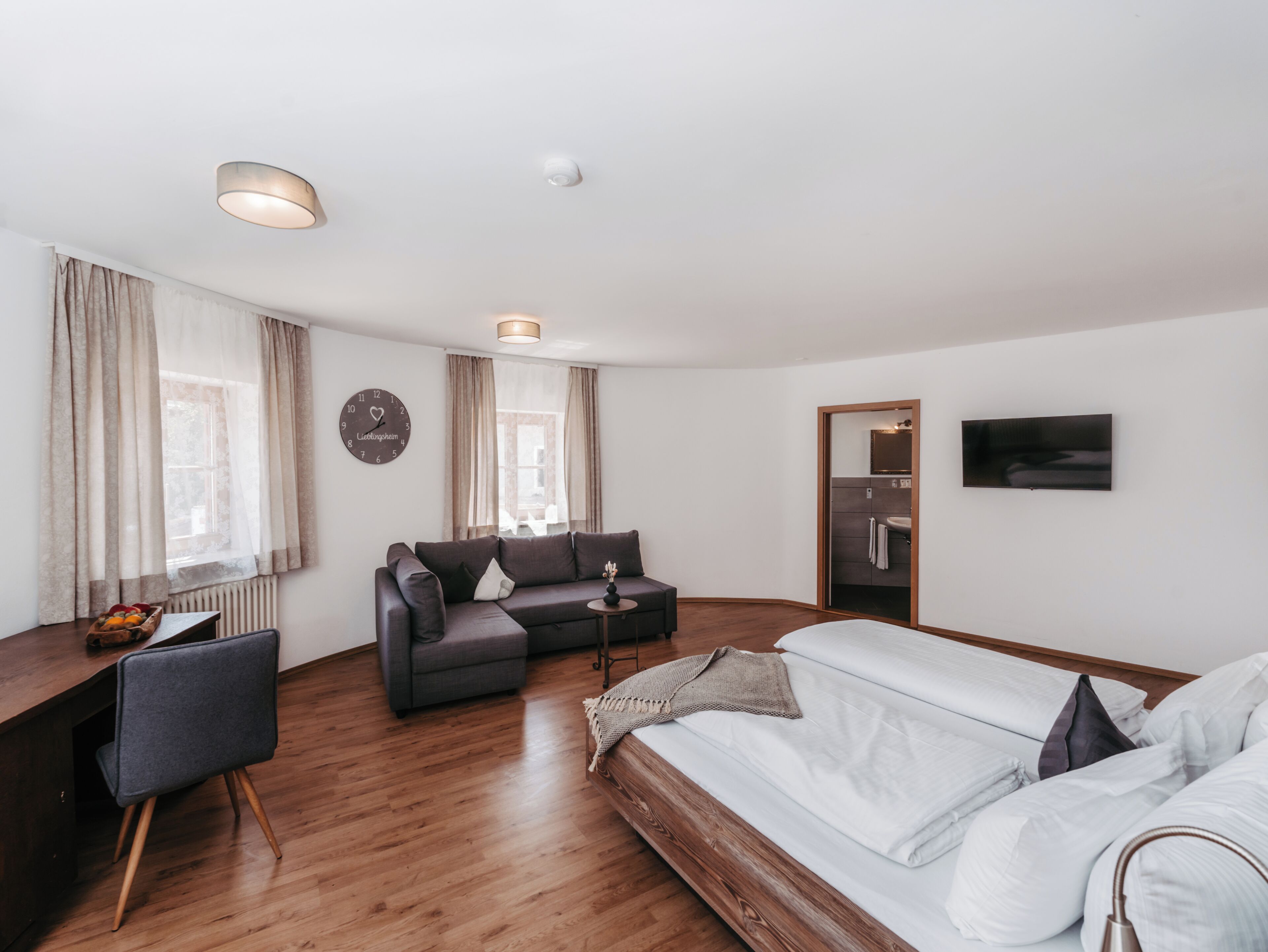 Ein modernes Wohnzimmer mit Sofa, Bett, Fernseher und Essbereich.