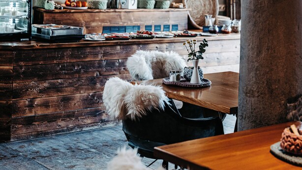 Un interior rústico con un arco de ladrillo, una cabeza de venado montada en la pared, muebles de madera y una exhibición de pasteles.