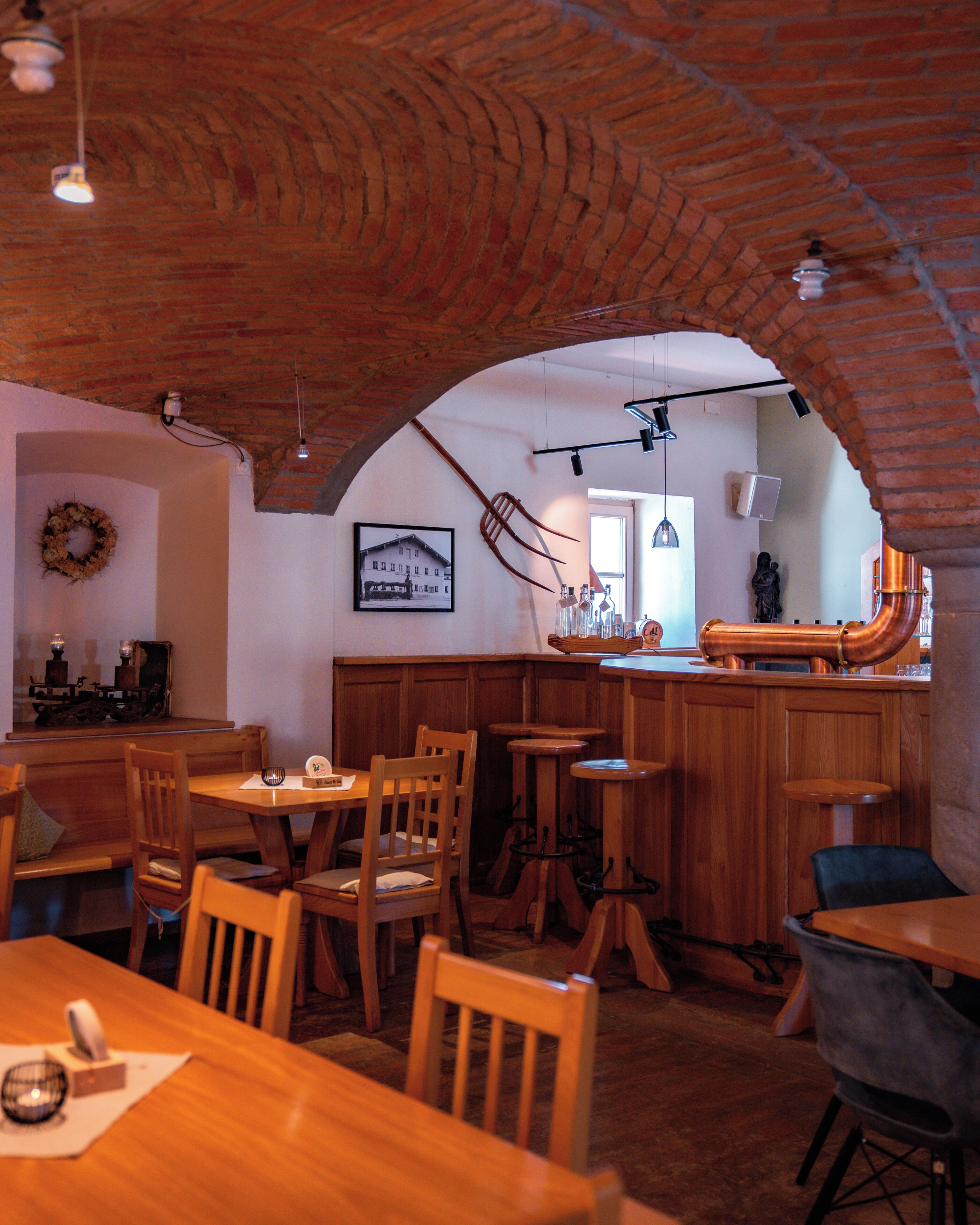 Un restaurant avec des meubles en bois, un plafond en briques et un coin bar.