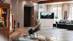 Una sala de estar amplia con un televisor grande, vigas de madera en el techo, un sofá cómodo y una chimenea.
