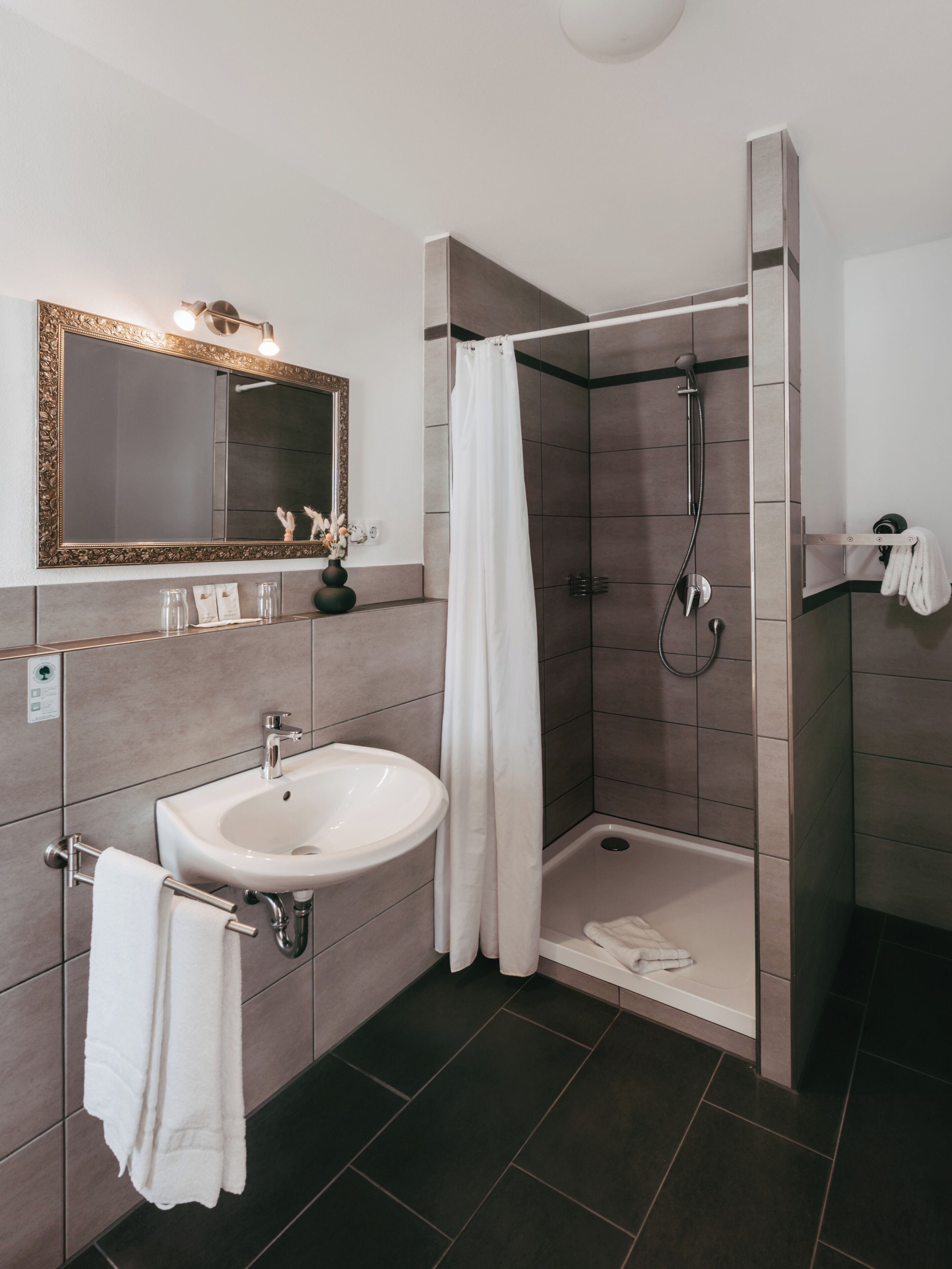 Ein modernes Badezimmer mit Waschbecken, Spiegel, Dusche und Handtuchhalter.
