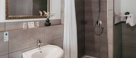 Ein modernes Badezimmer mit Waschbecken, Spiegel, Dusche und Handtuchhalter.