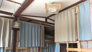 Een rustiek houten interieur met een tweepersoonsbed, een houten ladder en een plafondventilator.