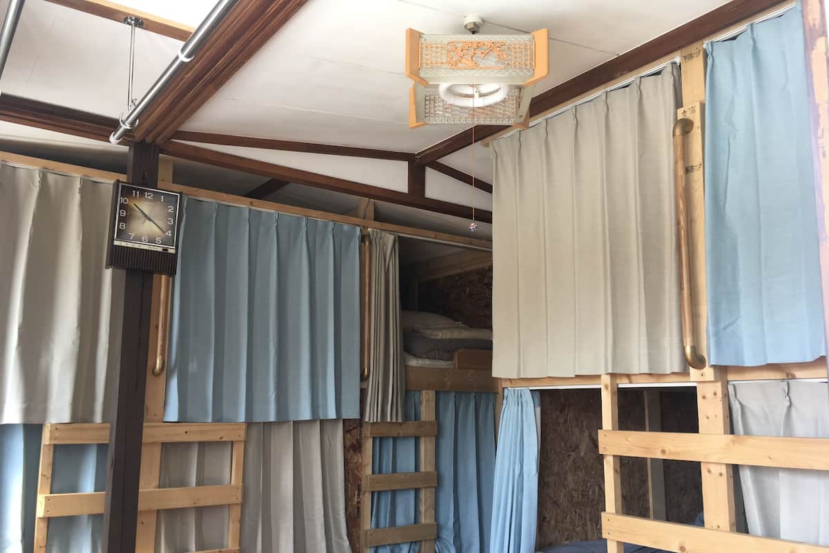 Interior rústico de una cabaña con una cama litera de madera, una escalera de madera y un ventilador de techo.