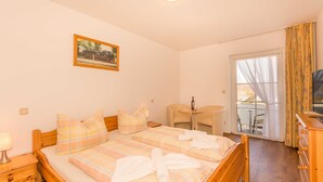 Une chambre d’hôtel avec deux lits, une petite table, une chaise, une télévision et un balcon avec des rideaux.