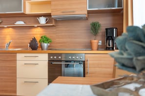 A modern kitchen with wooden cabinets, a stainless steel oven, and a coffee maker.