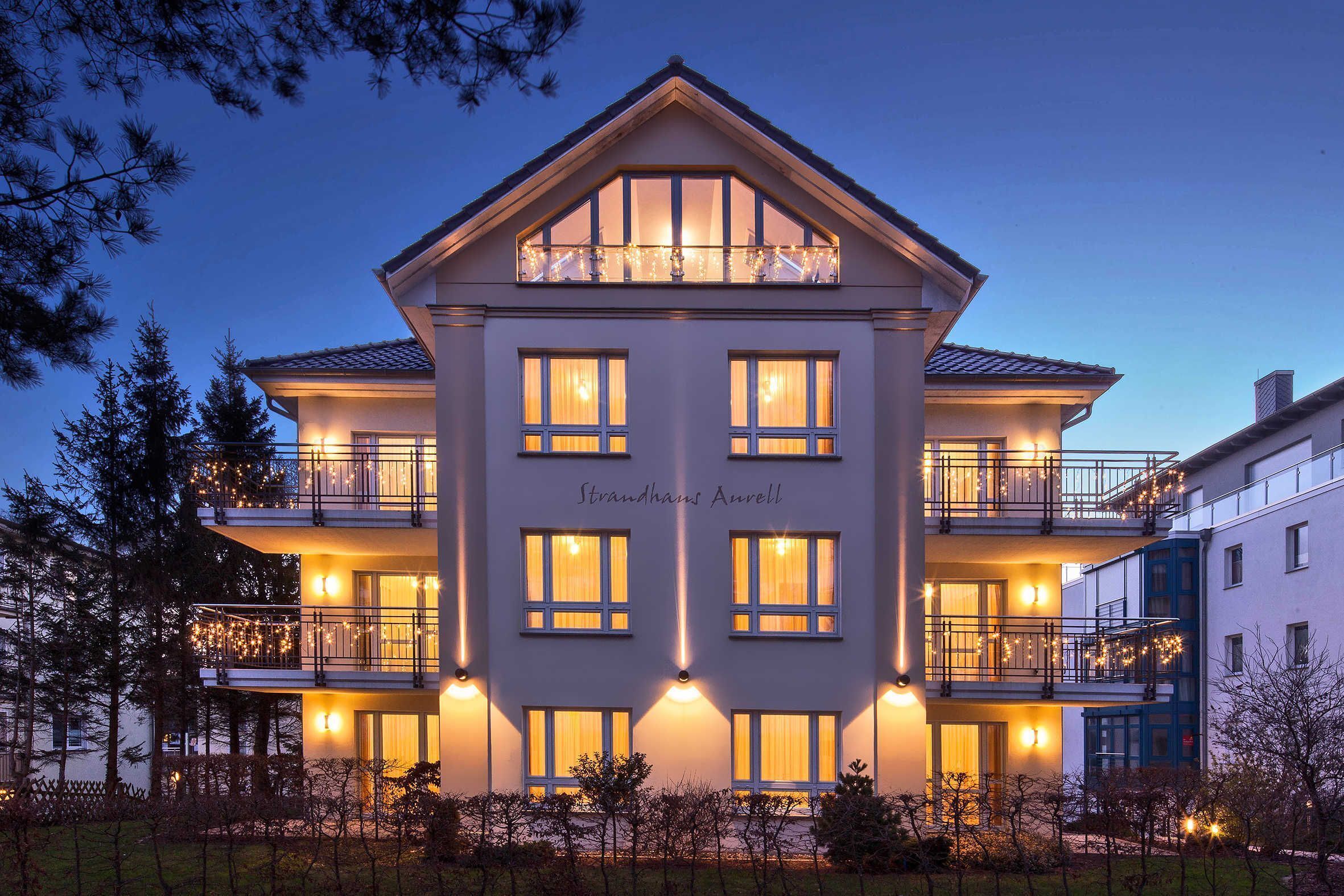 A multi-story hotel with a symmetrical facade, balconies with railings, and warm interior lighting.