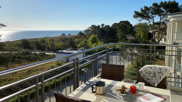 Un balcon équipé d’une table, de chaises, d’une bouilloire, d’une tasse et d’un menu.