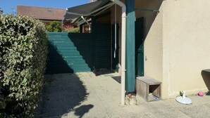 A residential building with a covered porch, a green door, and a small wooden structure.