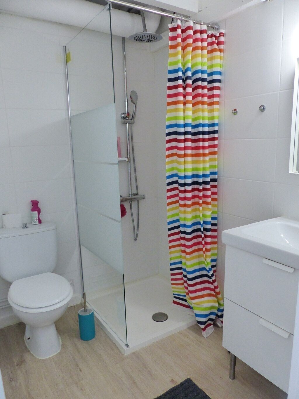 A bathroom with a glass-enclosed shower, a white toilet, and a white sink.