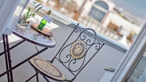 Un balcón con una mesa, sillas y una botella de vino.