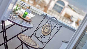 Een balkon met een tafel, stoelen en een fles wijn.