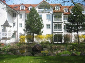 A multi-story building with balconies, a garden with rocks and plants, and a pond. - 2 Room B 010 - Wohnpark Binz (with indoor pool) (Binz)