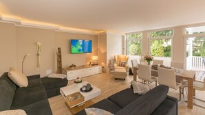 Un salon moderne comprenant un canapé, une table basse, un téléviseur et un coin repas.