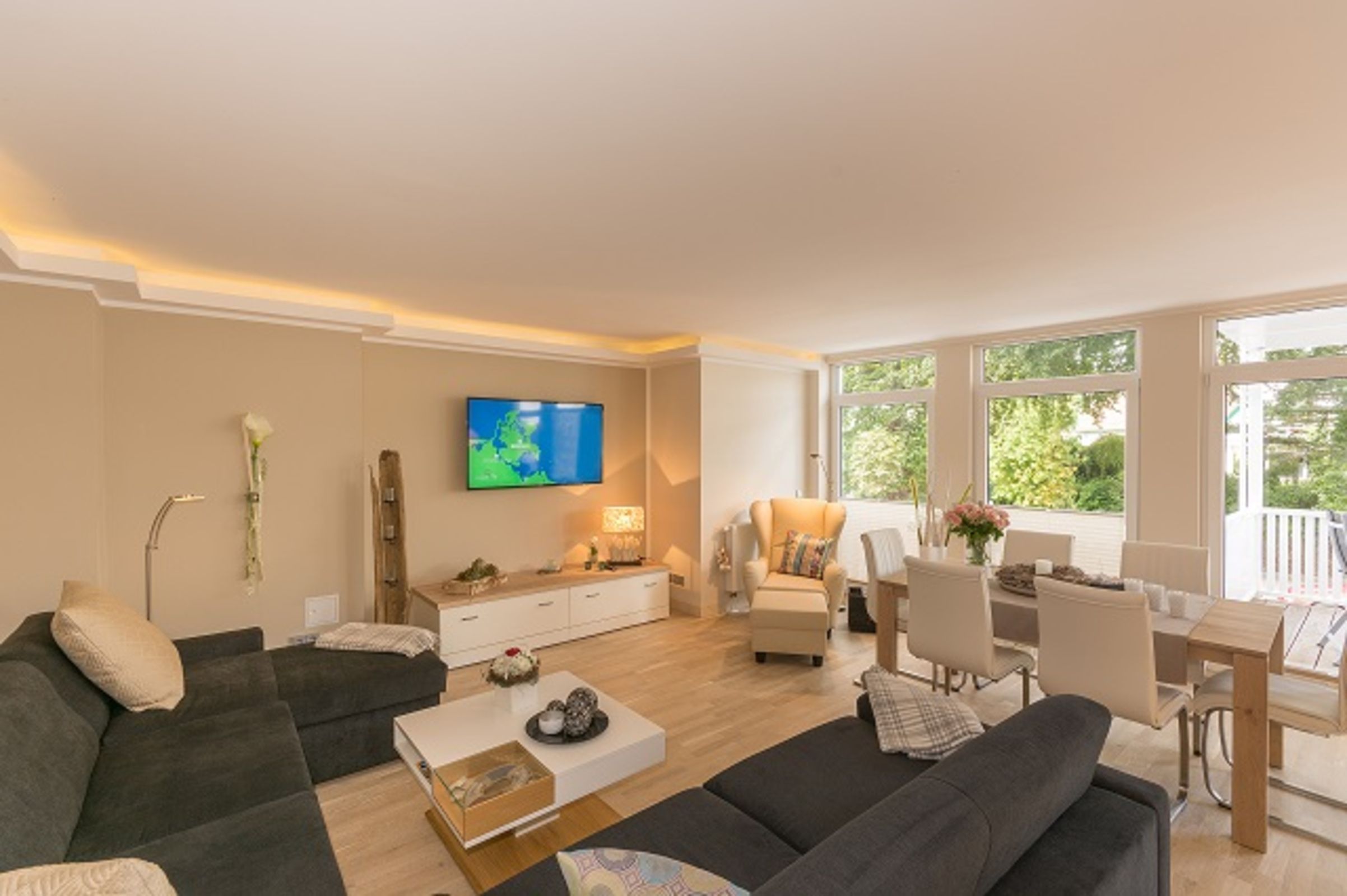 Una sala de estar moderna con sofá, mesa de centro, televisor y comedor.