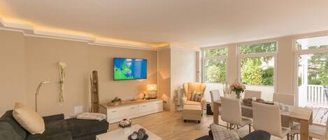 Una sala de estar moderna con sofá, mesa de centro, televisor y comedor.