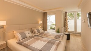 Une chambre d’hôtel avec un grand lit, deux lampes de chevet, une fenêtre donnant sur un beau paysage et une petite plante.