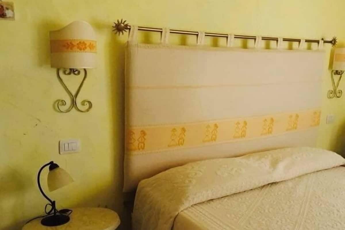 Une chambre à coucher avec un lit, une table de chevet avec une lampe et un luminaire fixé au mur.