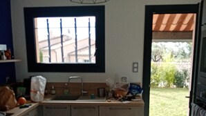 Cozinha moderna com armários de madeira, ilha embutida, janela com vista e luminária pendente.