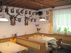 Un coin repas avec des bancs à rayures, une table recouverte d’une nappe blanche et des trophées d’animaux accrochés au mur.
