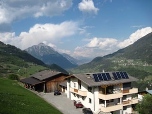 A modern two-story building with a garage, solar panels, and a view of mountains. - Bauernhof Huber - Double room 1 (Wenns)