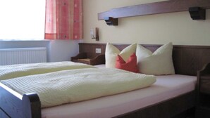 Un lit double avec une tête de lit en bois, une table de chevet et une lampe fixée au mur.