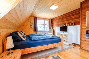Un dormitorio rústico de cabaña de madera con literas, un escritorio, una lámpara y un televisor.