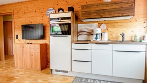 Eine moderne Küche mit Holzvertäfelung, einem Einbauofen, einem Flachbildfernseher und einem Spülbecken.