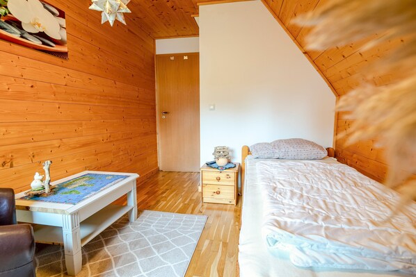 Ein Zimmer mit Holzwänden, einem Bett, einem Nachttisch, einem Tisch mit einer Karte und einem Stuhl.
