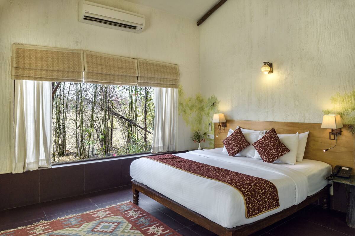 Une chambre d’hôtel avec un grand lit, une fenêtre avec des rideaux, une lampe de chevet et un luminaire fixé au mur.