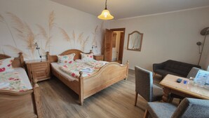 A bedroom with a wooden bed, a nightstand, a chair, a table, and a lamp. - 4 - "Up'n Hoff", Germany (Middelhagen)