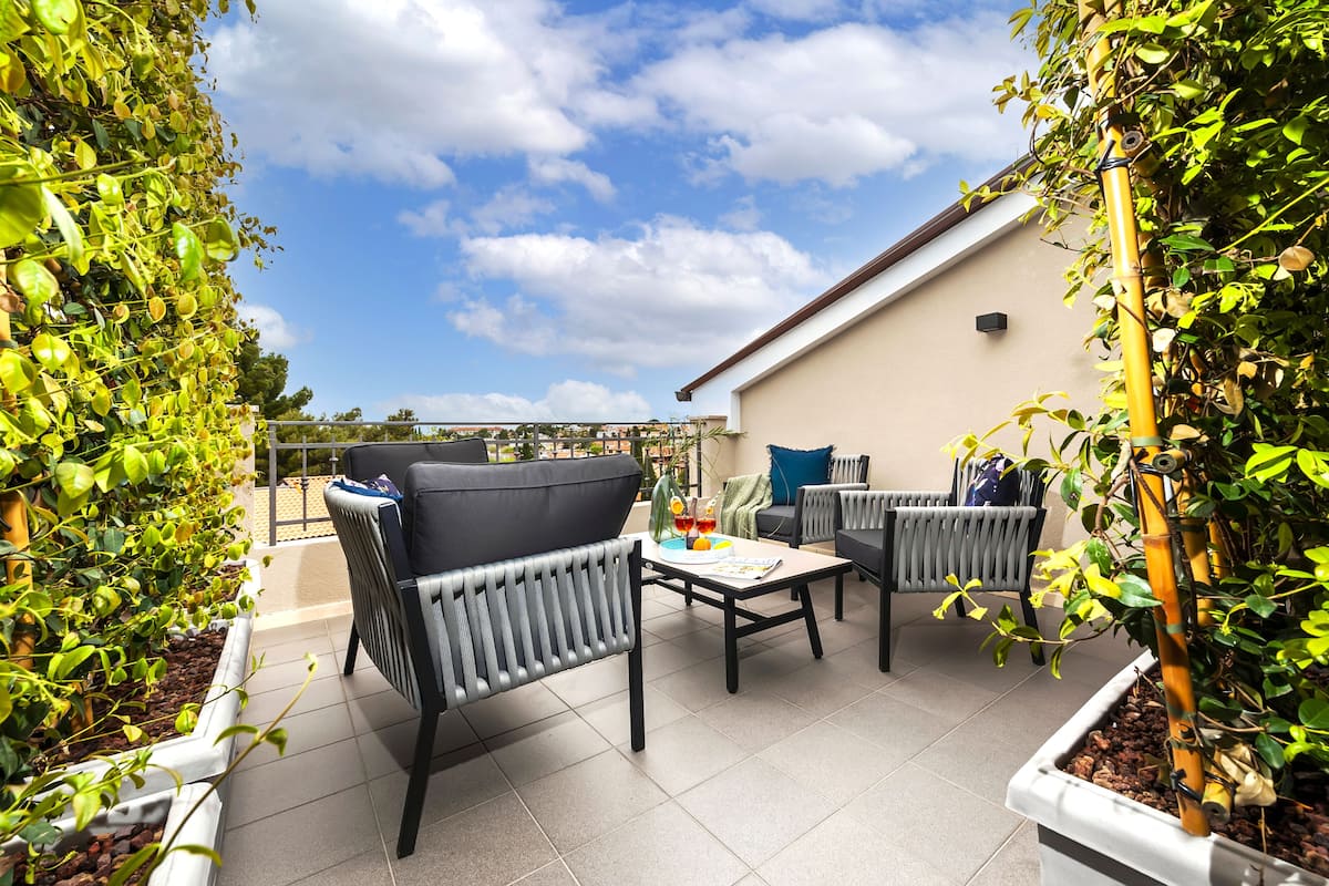 A patio area with outdoor furniture, a table, and potted plants.