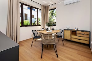 A modern dining area with a round table, four chairs, a buffet cabinet, and a potted plant. - Villa Tomo (Rovinj)