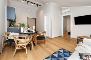 A modern living room with a dining area, wooden flooring, and a flat-screen TV mounted on the wall. - Villa Tomo (Rovinj)