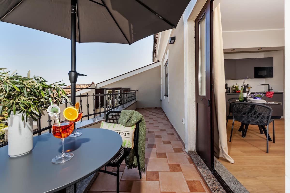 A balcony with a table, drinks, and a potted plant.