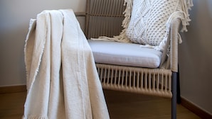 A wicker chair with a cushion and a white throw blanket on the floor. - Villa Tomo (Rovinj)