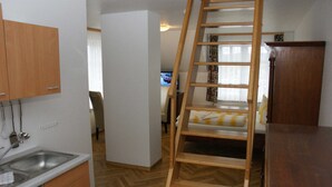 Eine kleine Küche mit Holzausstattung, integriertem Spülbecken und einer Holzleiter zu einem Schlafplatz in der Mansarde.