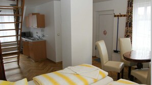 Ein Hotelzimmer mit Bett, Schreibtisch, Stuhl, einer kleinen Küche und einer Tür mit Rauchverbot-Schild.