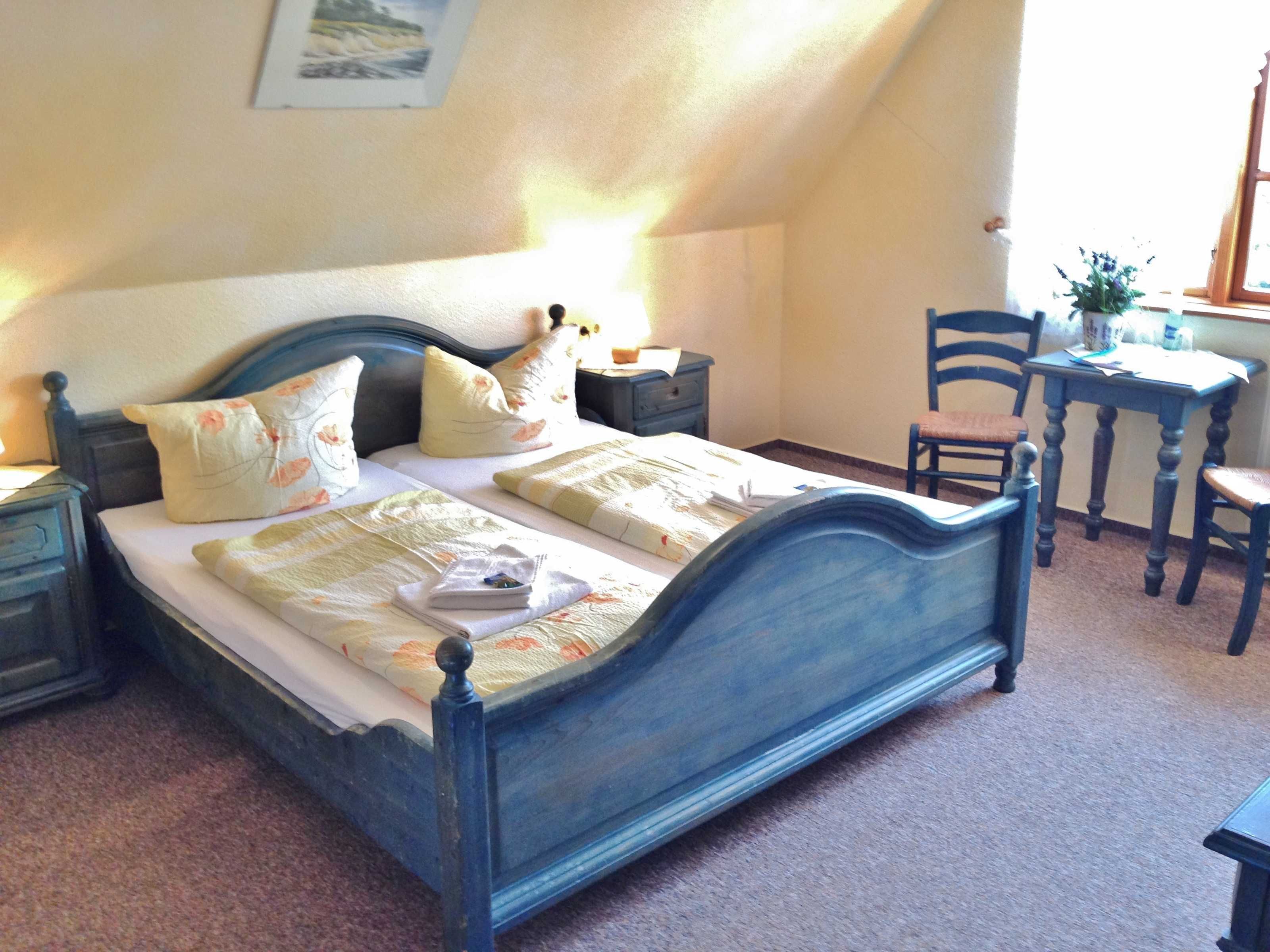 Ein Schlafzimmer mit einem Bett, einem Nachttisch, einem Stuhl, einem Schreibtisch und einem Fenster.