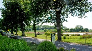 A landscaped area with pathways, trees, and a fenced field.