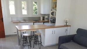 Una cocina moderna con una isla central, taburetes de bar, un sofá y una pequeña mesa.
