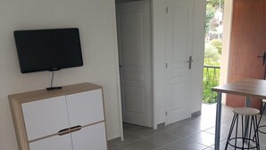 Una cocina moderna con televisor, un armario de madera y un área de comedor con una mesa y dos sillas.