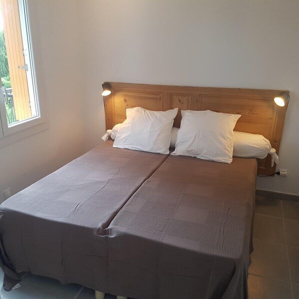 A double bed with a wooden headboard and two bedside lamps.