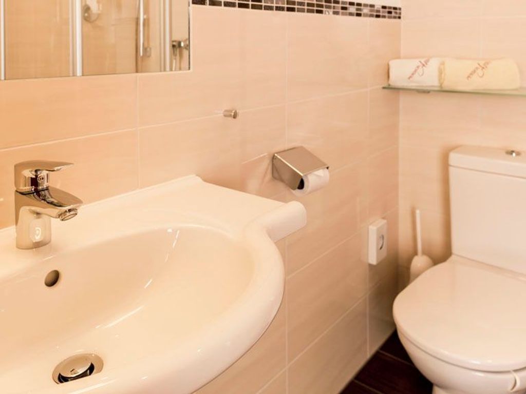 Een badkamer met een wastafel, toilet en spiegel.