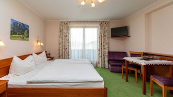 Une chambre d’hôtel avec un lit, un bureau et une chaise, une télévision et une fenêtre avec des rideaux.
