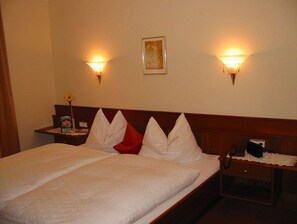 Habitación de hotel con cama, mesitas de noche y lámparas fijadas a la pared.