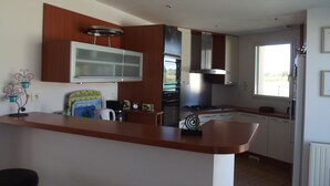 A modern kitchen with a central island, built-in appliances, and a window providing natural light. - House in the heart of the marshes (Saillé Guérande)