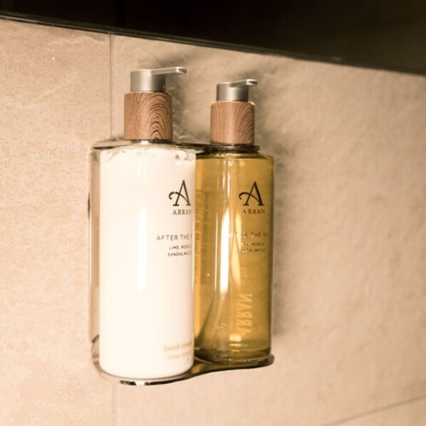 Dos botellas de crema de manos con dosificador de madera, una con la etiqueta 'After the Rain' y la otra 'After the Sun', ambas con la marca 'A' y 'ARRAN'.